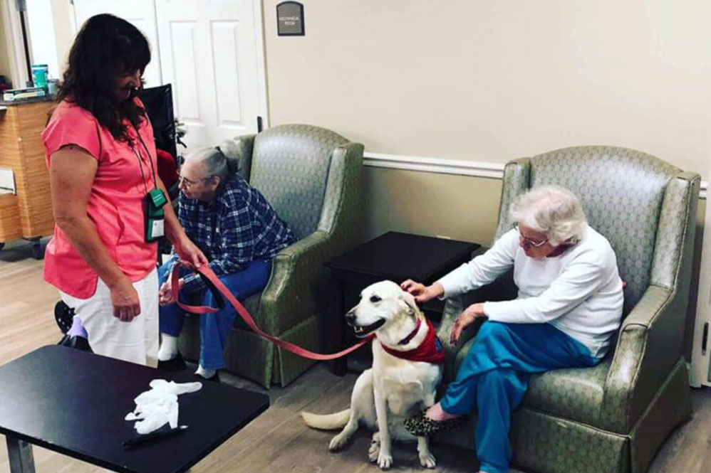 Gardens of Savannah residents and staff member playing with dogs